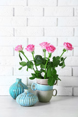 Beautiful roses and vases on brick wall background