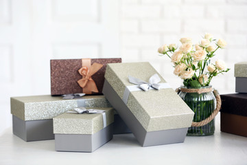 Naklejka premium Beautiful gift boxes with bouquet of flowers on the table in front of brick wall, close up