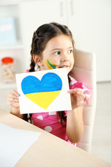 Cute little girl with picture on home interior background