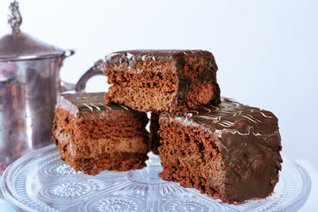 Served table with a teapot and chocolate cakes on white background