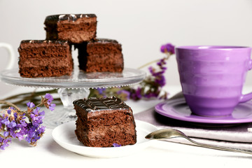 Served table with chocolate cakes and a cup of tea on white wooden background