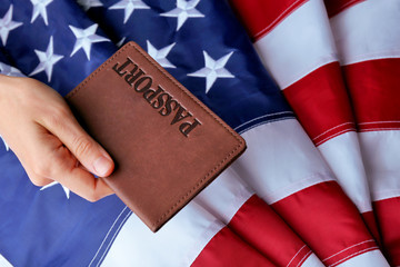 Fototapeta na wymiar A hand holding the passport on American Flag background