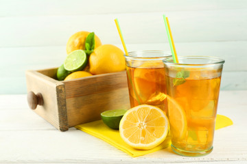 Iced tea with lemon on light wooden background