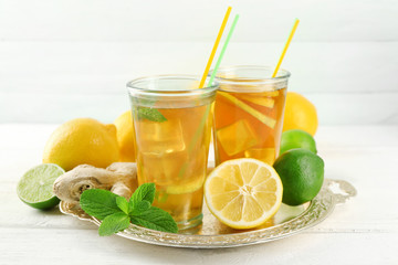 Iced tea with lemon on light wooden background