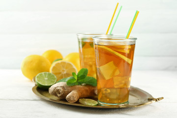 Iced tea with lemon on light wooden background