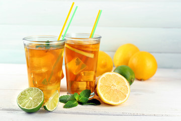 Iced tea with lemon on light wooden background