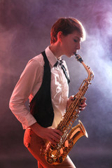 Naklejka na ściany i meble Talent woman professionally plays saxophone in red smoke