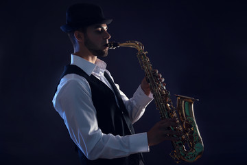 Naklejka na ściany i meble Elegant saxophonist plays jazz on dark background