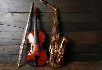 Naklejka premium Musical instruments: saxophone, violin and flute on wooden background