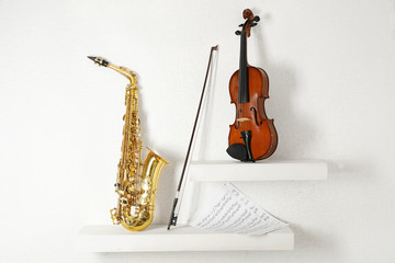 Musical instruments on decorated shelves against white wall background