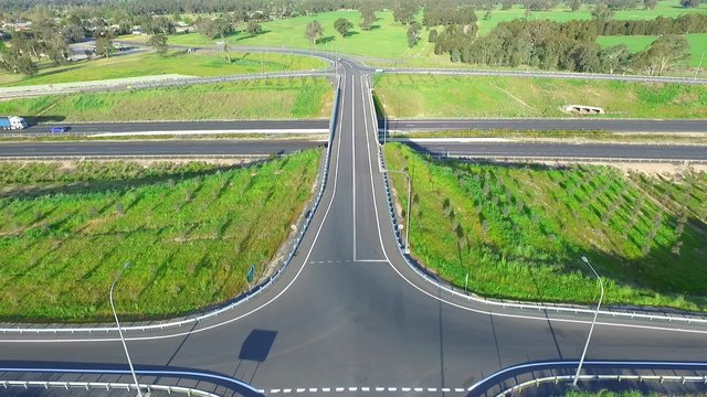 Elevated aerial view of freight b double semi trailer lori trucks, vehicles and cars traveling on high speed freeway or motorway. Hume Highway Australia featuring interchange and road overpass.