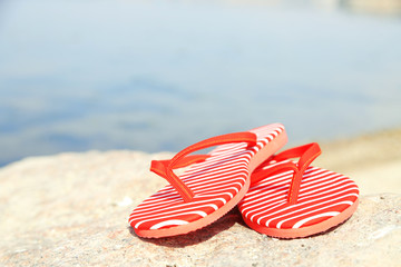 Bright flip-flops on stone, nature background