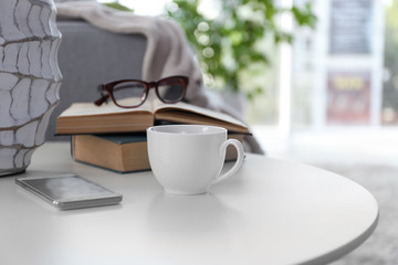Cup of coffee with books on table in room