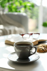 Cup of coffee with biscuits on table in room