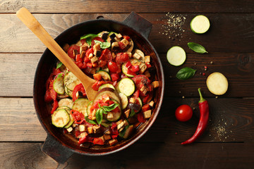 Tasty vegetarian ratatouille made of eggplants, squash, tomatoes and onions in black cast iron pan,...