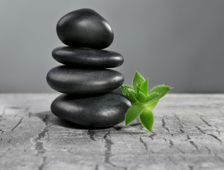 Pile of pebbles with leaf on the table against grey background