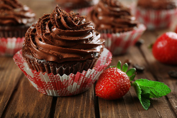 Chocolate cupcakes and strawberries on wooden background