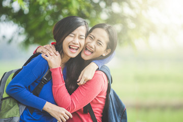 Two young Asian students laugh, joking around together