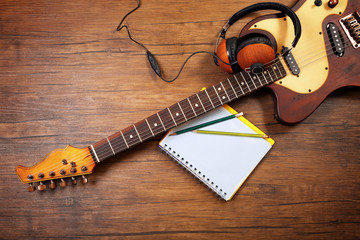 Naklejka premium Electric guitar and headphones on wooden background