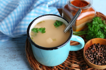 Mug of soup on wicker mat on a table
