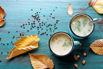 Two mugs of soup on blue wooden background