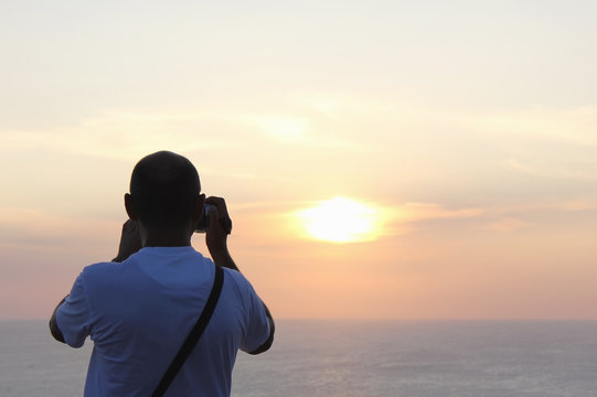 Tourist leads shooting setting sun on the camera