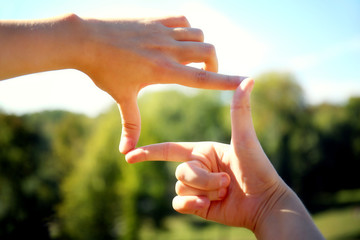 Fingers in the form of frame on nature background