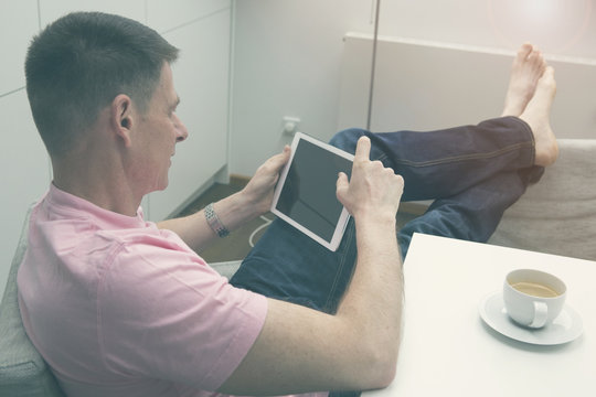 man sitting at table with coffee and tablet