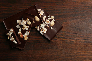 Chocolate pieces with nuts on color wooden background