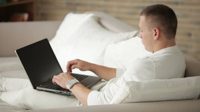 Young man relaxing on sofa and using laptop