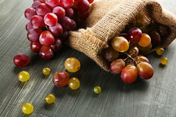 Juicy purple grapes in sack pouch, on wooden background