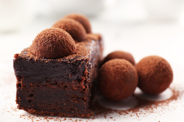Slice of chocolate cake with a truffle on plate closeup