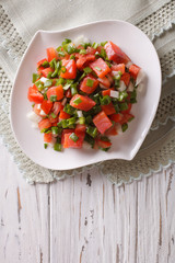 Hawaiian lomi lomi salad close-up on the table. vertical top view
