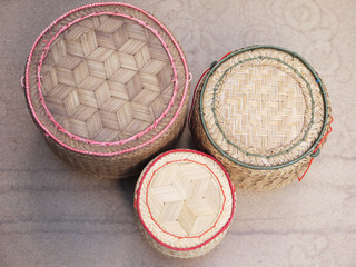 hand craft handmade bamboo weaving Thai sticky rice round box on a colorful reed mat for sale in a traditional lifestyle village