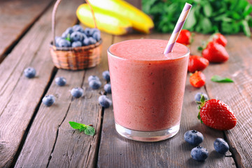 A glass of fresh cold smoothie with berries, on wooden background