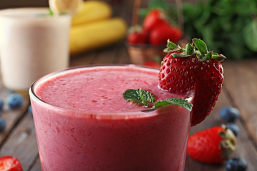 Glasses of fresh cold smoothie with fruit and berries, on wooden background, close-up