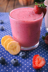 Glasses of fresh cold smoothie with fruit and berries, on blue tablecloth background