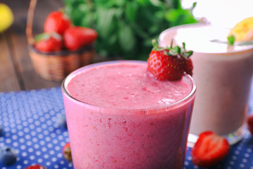 Glasses of fresh cold smoothie with fruit and berries, on blue tablecloth background, close-up