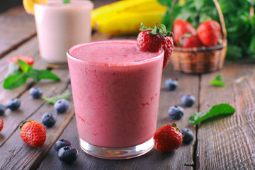 Glasses of fresh cold smoothie with fruit and berries, on wooden background
