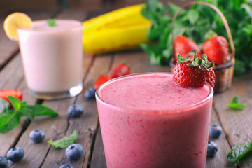 Glasses of fresh cold smoothie with fruit and berries, on wooden background, close-up