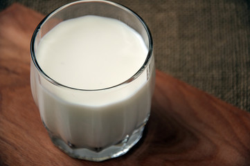 A glass of milk on wooden board on a background sacking, burlap,