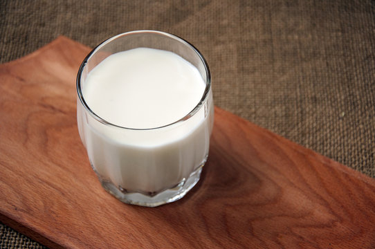 A glass of milk on wooden board on a background sacking, burlap,