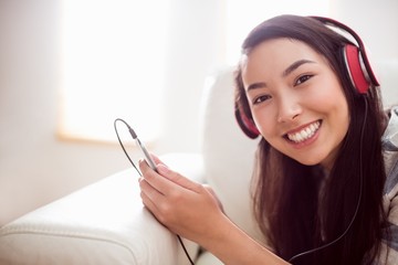 Smiling asian woman on couch listening to music