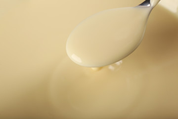 Background of condensed milk and a spoon in a bowl, close-up