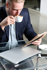 Young attractive businessman having lunch and working in a cafe