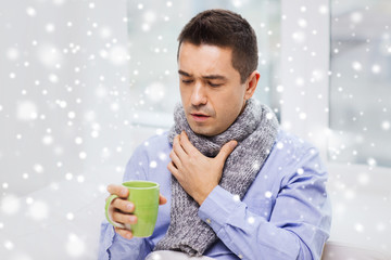 ill man with flu drinking tea and coughing at home