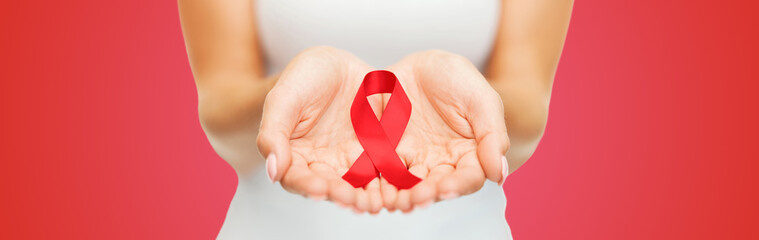 close up of hands with red AIDS awareness ribbon