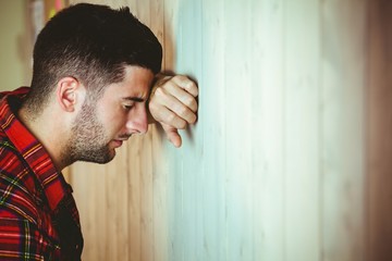 Stressed man leaning against wall