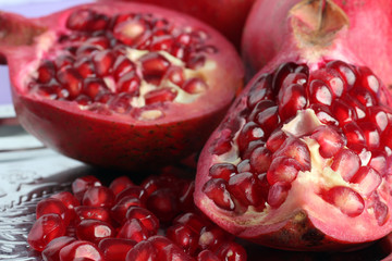 very juicy and big and delicious pomegranate in the section in the tray isolated on purple background