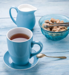 Cup of tea, milk jug and cane sugar cubes.
